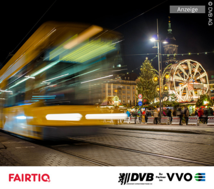 Verschwommene Straßenbahn vor einem Weihnachtsmarkt bei Nacht